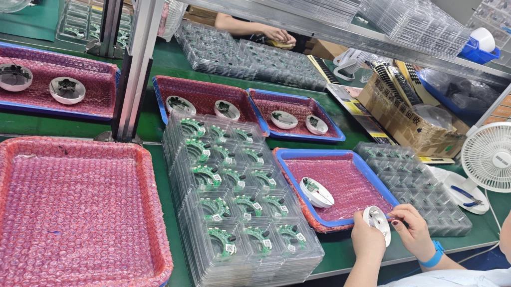 Clean and organized earphone assembly workstation with protective trays and cushioned pads for components.